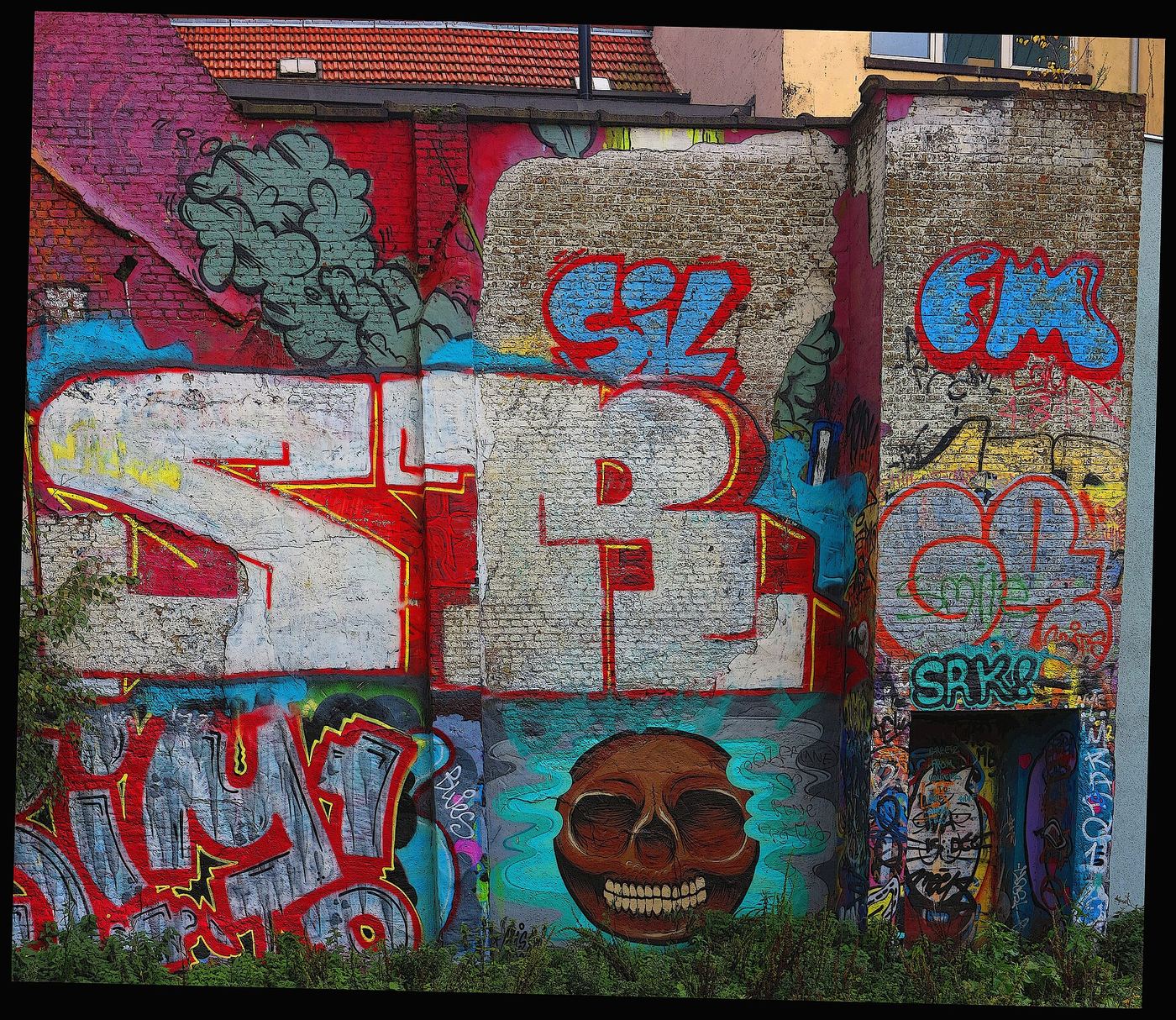 Wall densely covered with colourful graffiti pieces and characters