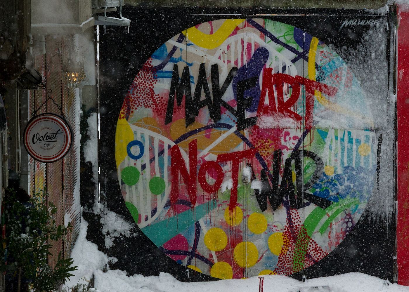 Round colourful mural with painted slogan lettering in a snowy courtyard