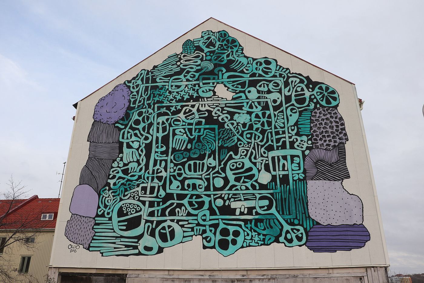 Teal maze-pattern mural covering the gable of a white building
