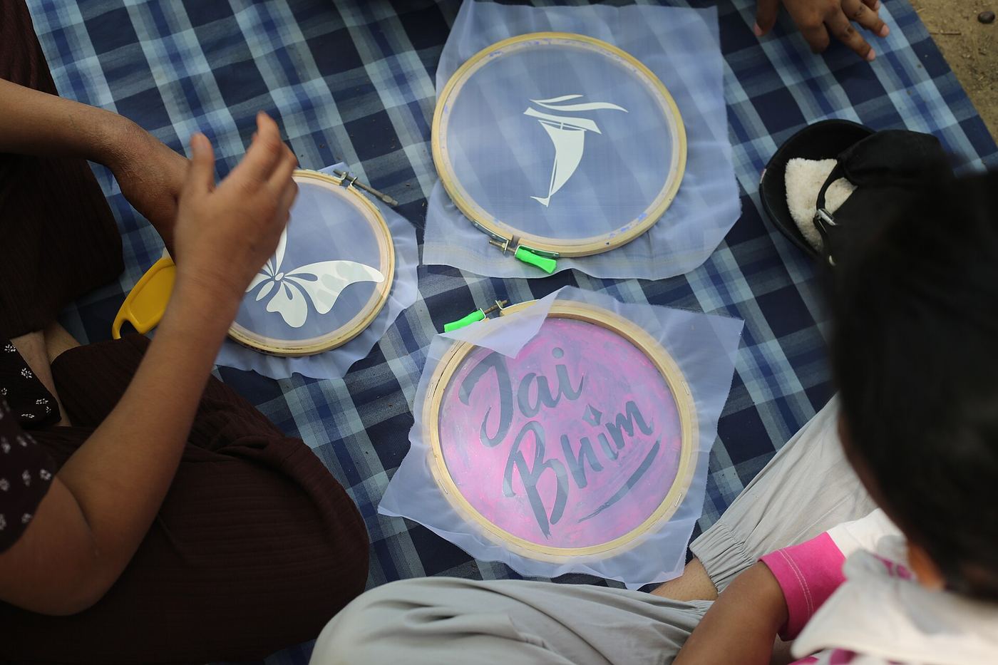 People printing designs onto fabric stretched in embroidery hoops