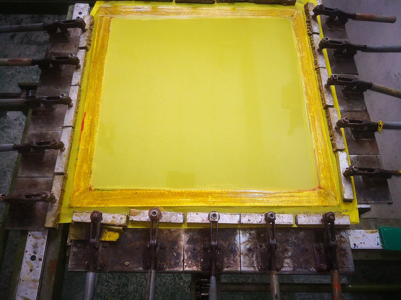 Yellow-coated silkscreen mesh stretched in a frame on a clamping table