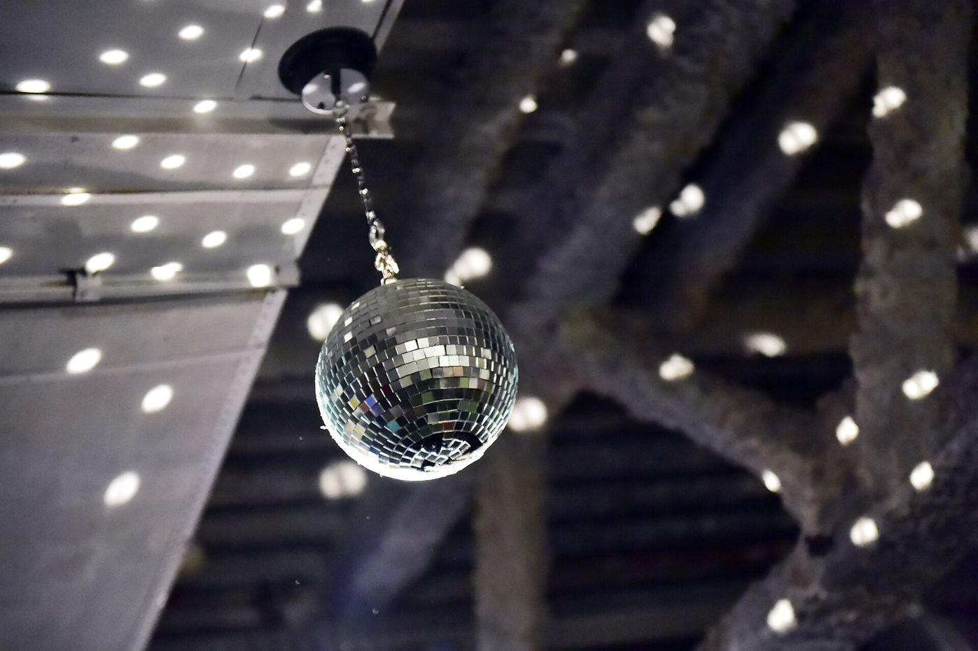 Mirror ball hanging among white lights on a dark ceiling