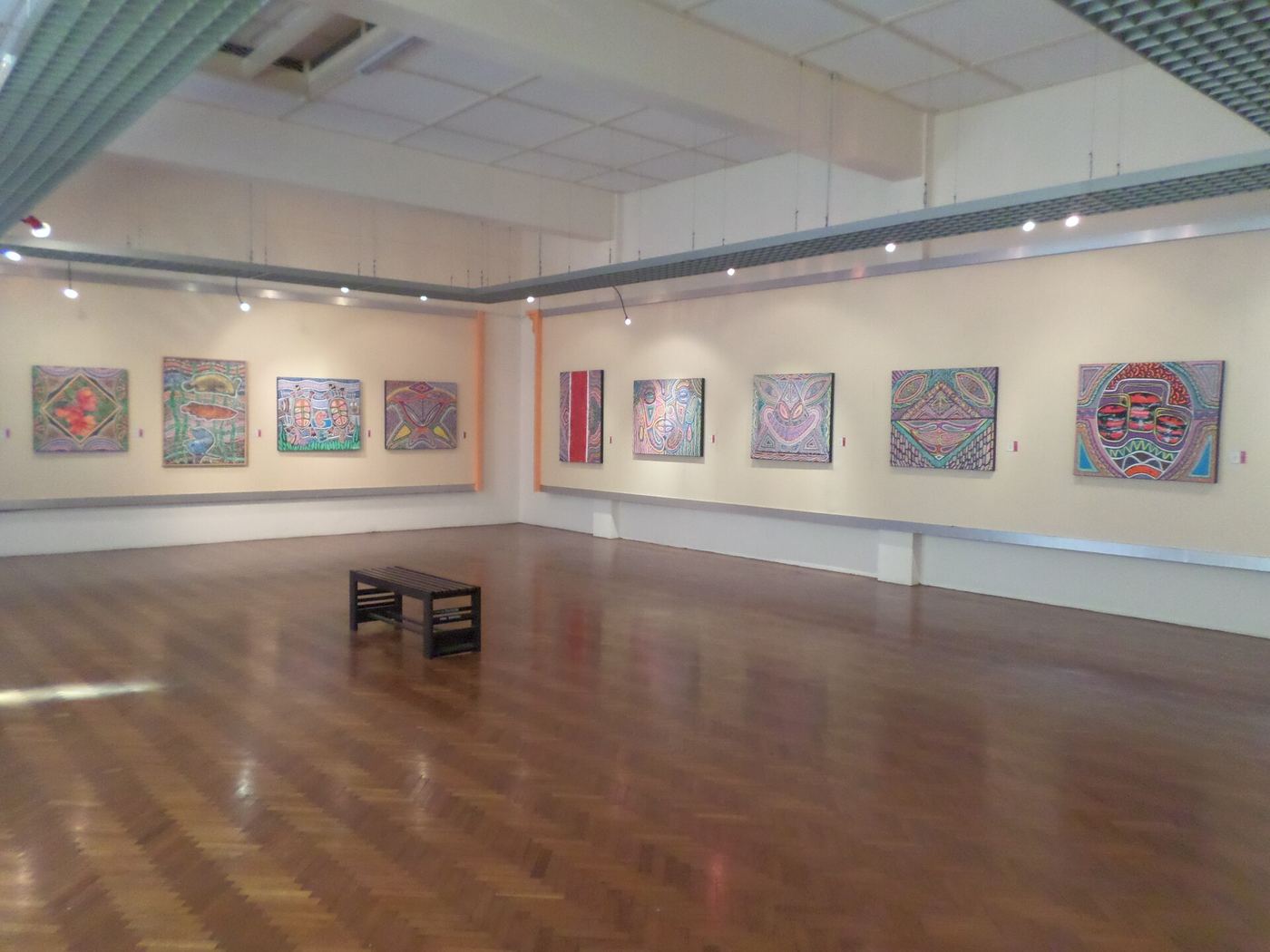Long gallery hall with colourful patterned paintings hung in a row