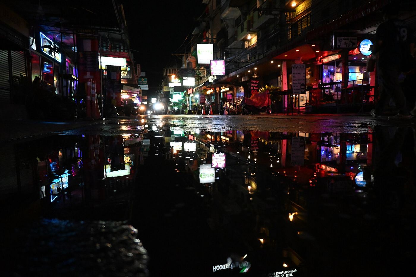 Neon-lit city street at night reflected in a puddle