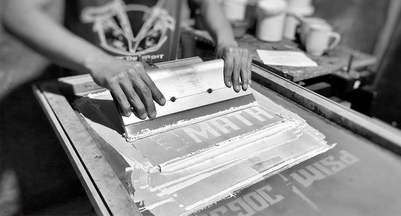 Black-and-white photo of hands preparing a silkscreen frame