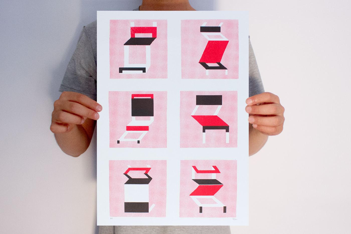 Person holding a pink and black risograph print of six chairs